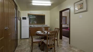 A compact kitchen with a microwave, dining table, and chairs.