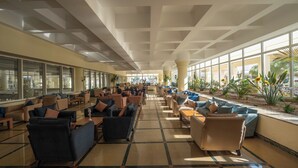 A spacious lobby with multiple seating areas, large windows, and a central column. - JAZ Royal Palmariva (Makadi Bay)