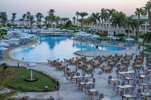 A resort with a large pool, lounge chairs, and outdoor seating areas. - JAZ Royal Palmariva (Makadi Bay)