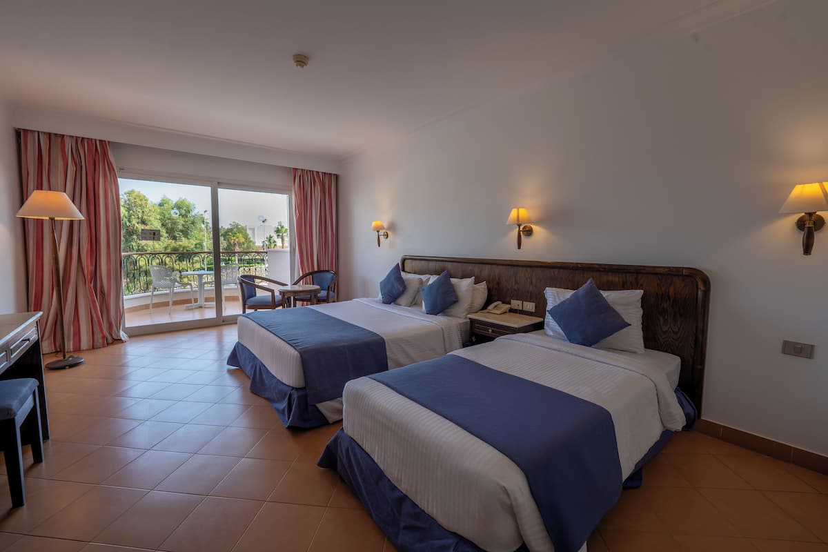 Una camera d'albergo con due letti, una scrivania e una sedia.