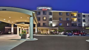 A Courtyard Marriott hotel with a modern design, multiple floors, and a parking area with several cars.