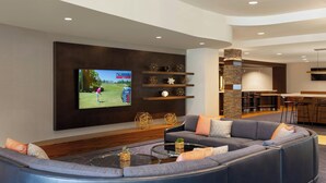 A modern living room with a large flat-screen TV, a gray sectional sofa, and a small coffee table.