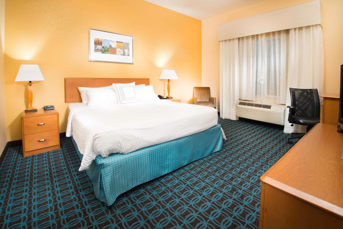 A hotel room with a bed, two bedside tables with lamps, a desk, and a chair.