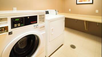 A laundry room with a front-loading washing machine, a dryer, and a wall-mounted ironing station.