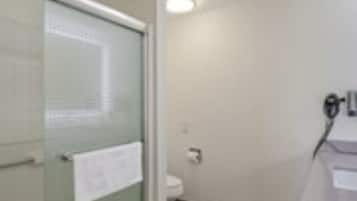 Un baño con puerta de vidrio, un inodoro y un lavabo con espejo.