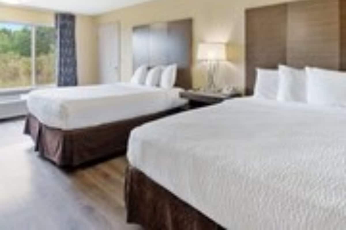 A hotel room with two beds, a large window, and a view of the outdoors.