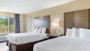 Ein Hotelzimmer mit zwei Betten, einem großen Fenster und Blick ins Freie.