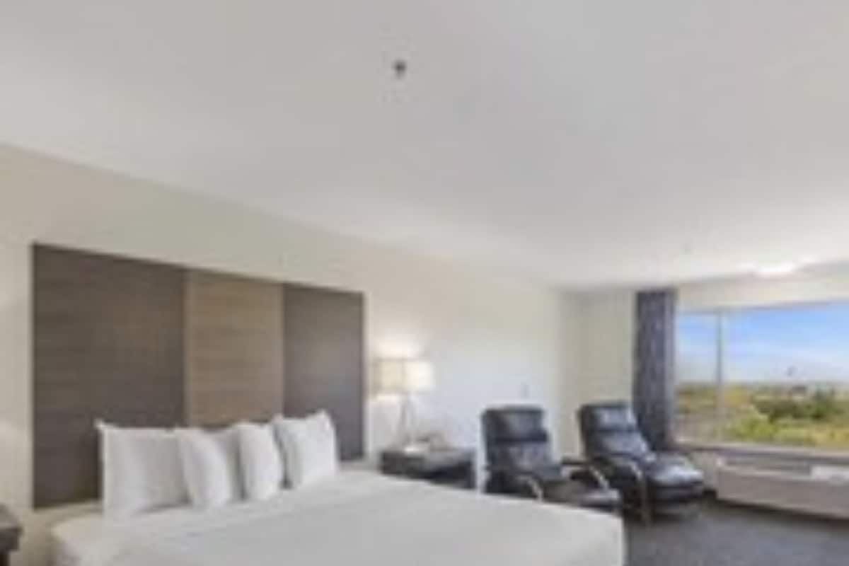 A hotel room with a large bed, a desk, a chair, and a window with a view.