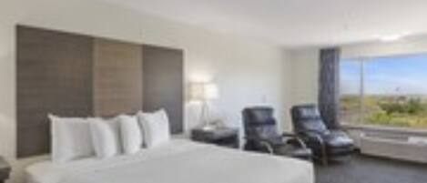 A hotel room with a large bed, a desk, a chair, and a window with a view.