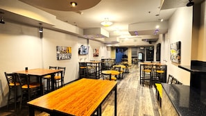 A restaurant interior with wooden tables and chairs, recessed ceiling lights, and artwork on the walls. - Baymont by Wyndham Las Vegas South Strip (Las Vegas)