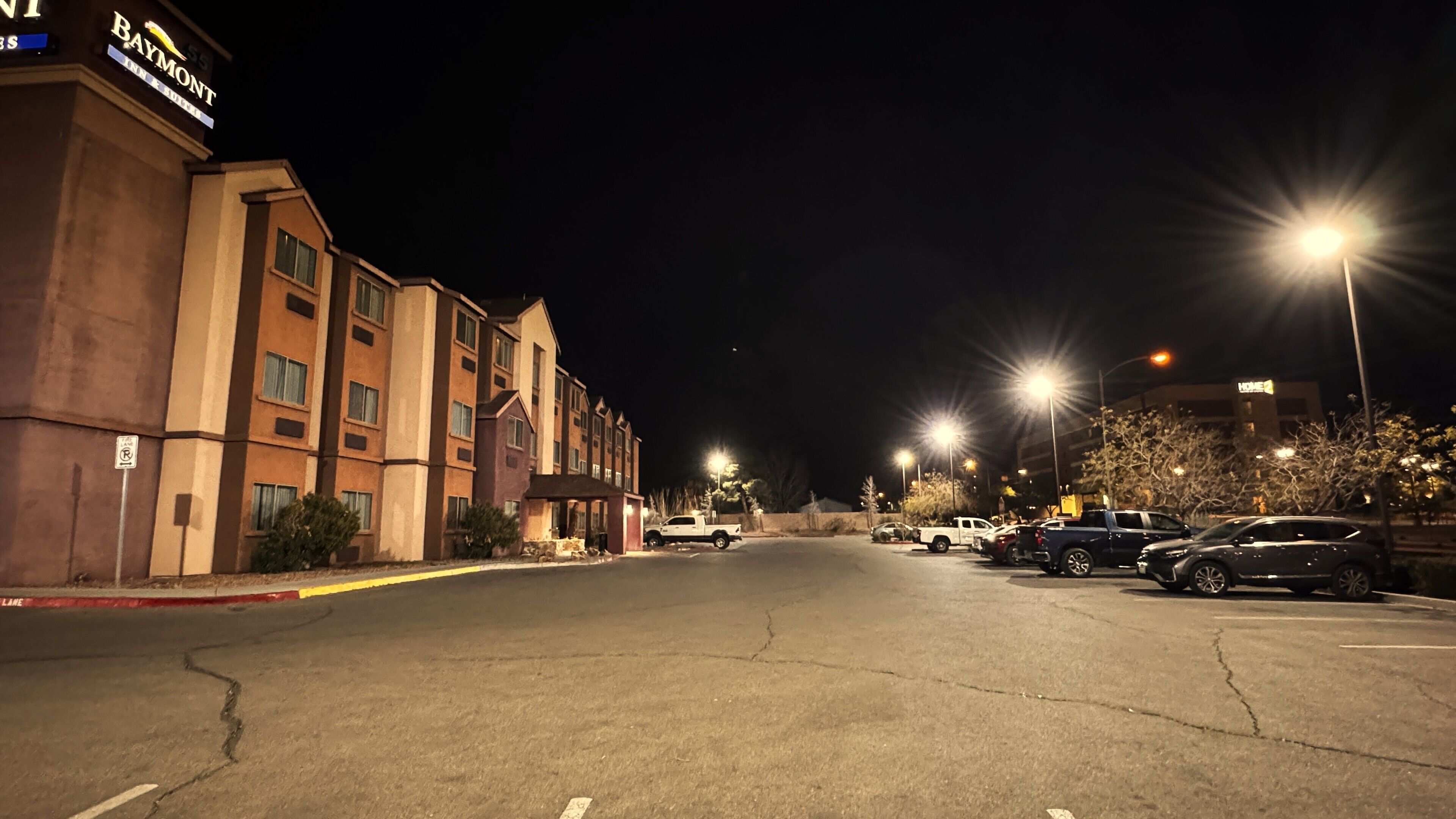 Un hôtel doté d’un parking, de plusieurs véhicules et d’un éclairage public la nuit.