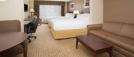 A hotel room with a large bed, a sofa, a desk, and a chair.