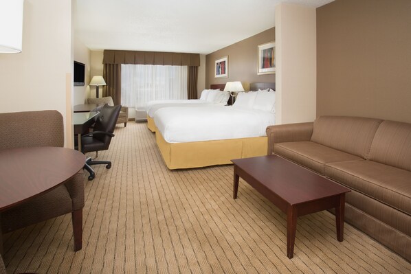 A hotel room with a large bed, a sofa, a desk, and a chair. - Holiday Inn Express & Suites Minot by IHG (Minot)