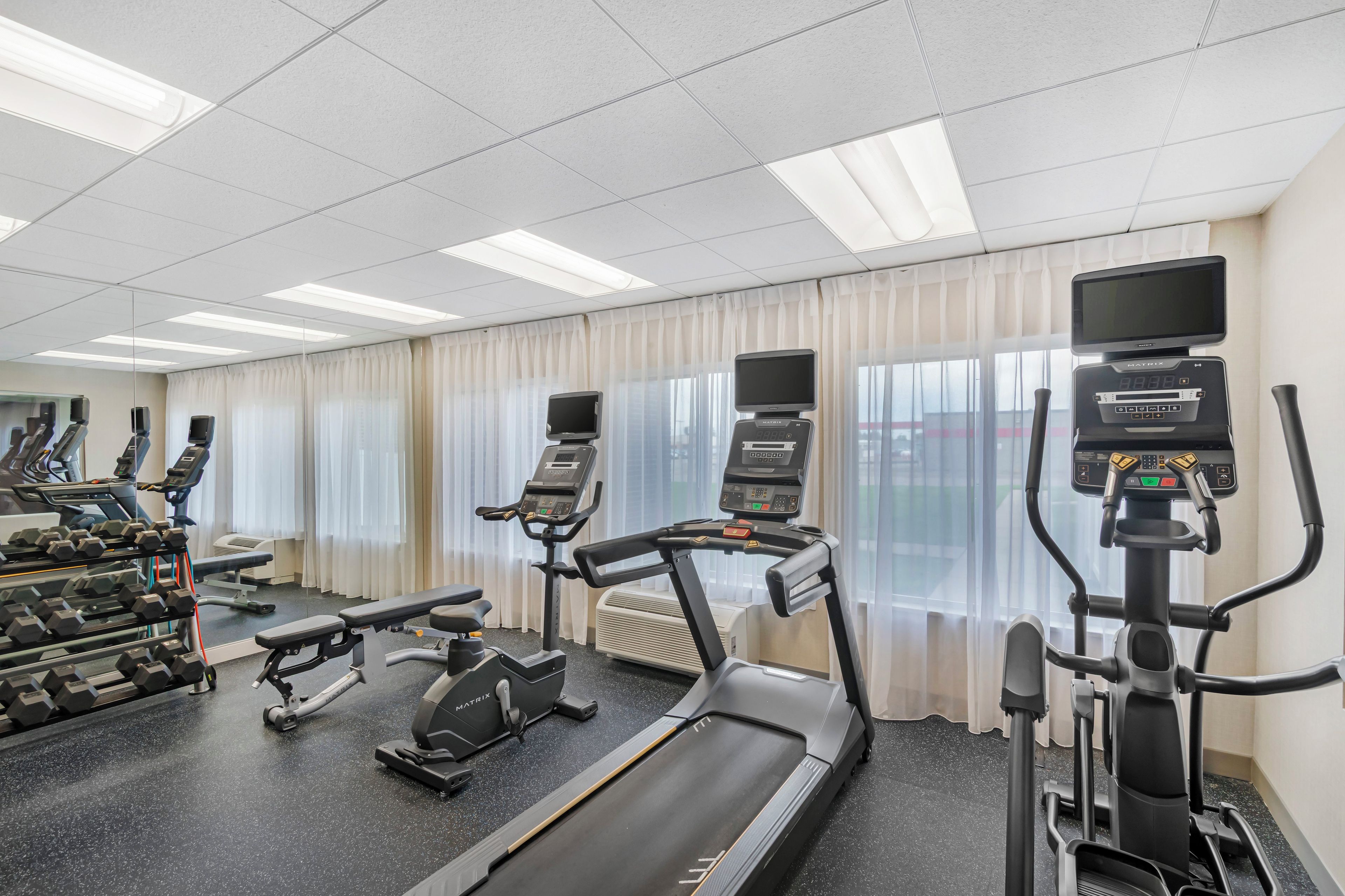 Une salle de sport équipée de tapis de course, de vélos elliptiques et de bancs de musculation.
