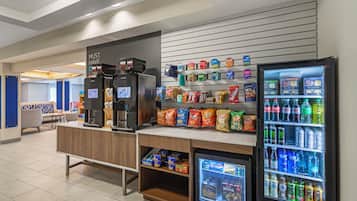 En bemanningsfri dryckesstation med kaffemaskiner, ett utbud av snacks och en kylskåpsförsedd dryckesautomat.