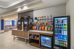 A self-service beverage station with coffee machines, snack options, and a refrigerated drink cooler. - Holiday Inn Express & Suites Minot by IHG (Minot)