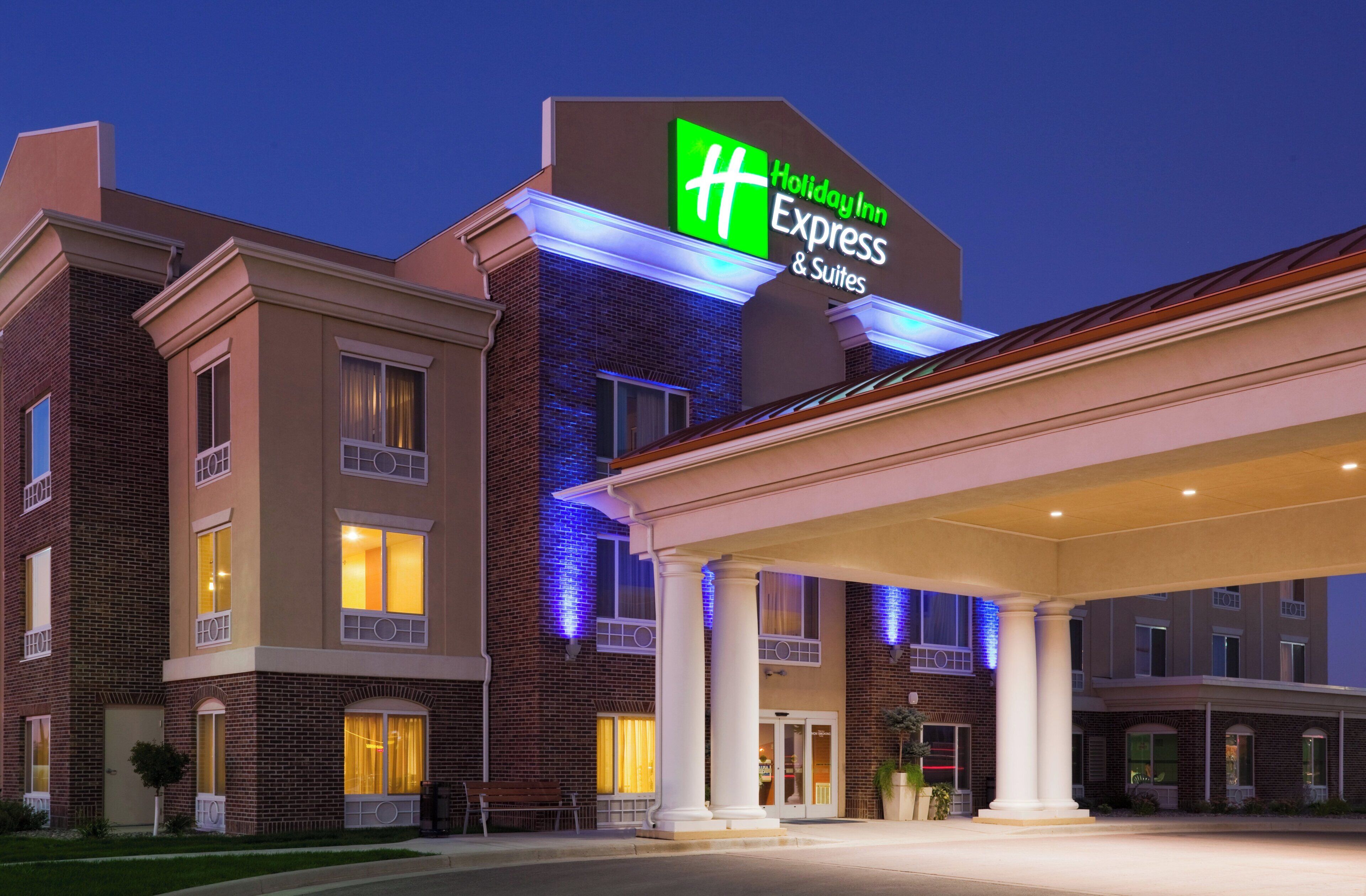 A Holiday Inn Express & Suites hotel with a brick facade, large windows, and a well-lit entrance.