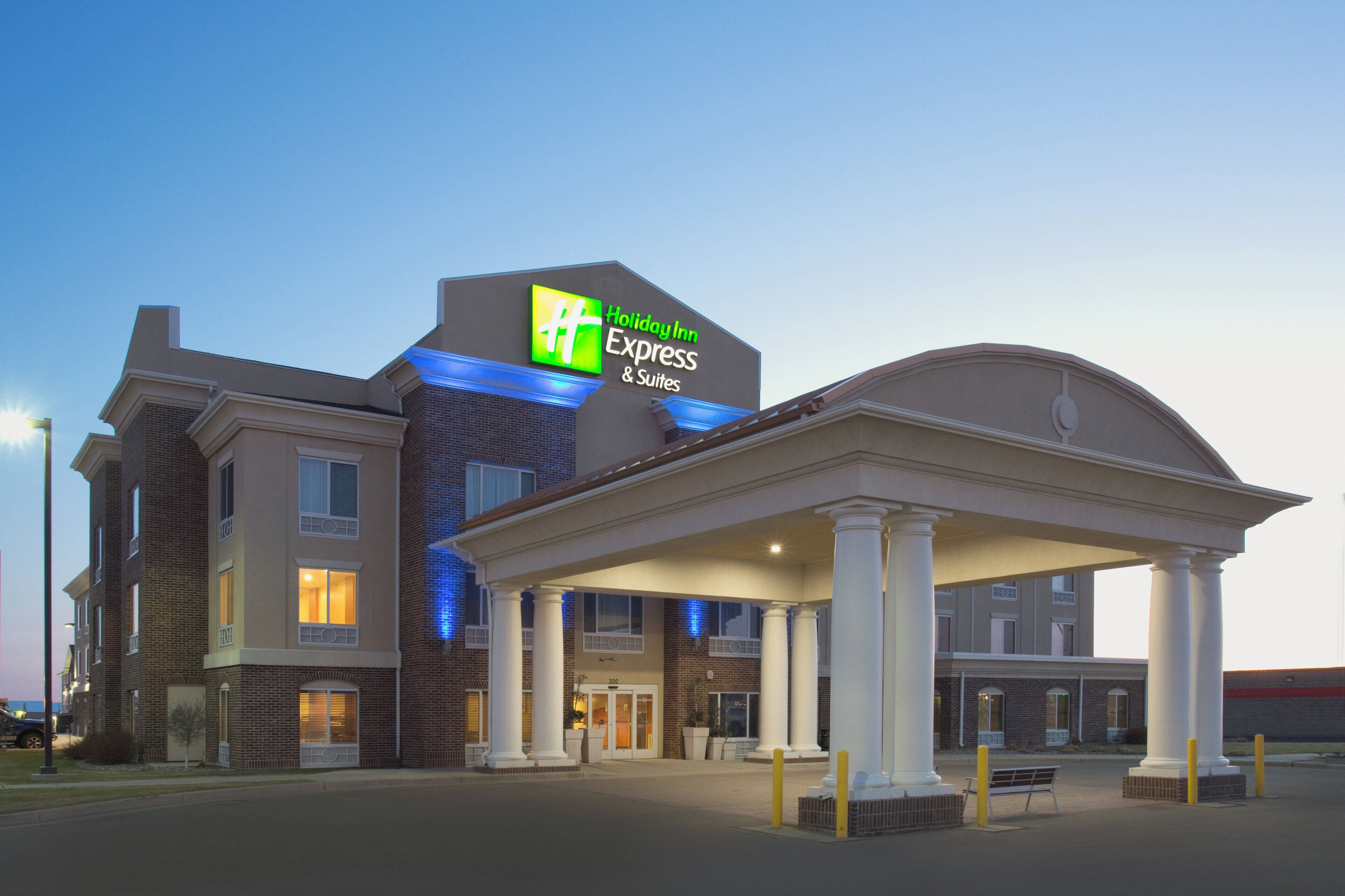 A Holiday Inn Express & Suites building with a prominent sign, a covered entrance, and a brick facade.