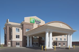 Edificio Holiday Inn Express con fachada de ladrillo, columnas grandes que sostienen una entrada cubierta y un cielo azul despejado.