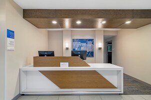 Una recepción de diseño moderno, un cartel que indica que la propiedad pertenece a Minot Lodging Group LLC y un horario de registro de entrada y salida.