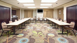 A conference room with a long table, chairs, a flat-screen TV, and a microwave in the corner. - Holiday Inn Express & Suites Minot by IHG (Minot)