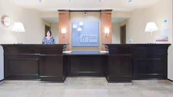 Een receptiebalie met een klok, twee wandlampen en een bord met Holiday Inn Express.