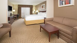 A hotel room with a bed, a sofa, a desk with a chair, a TV, and a painting on the wall. - Holiday Inn Express & Suites Minot by IHG (Minot)