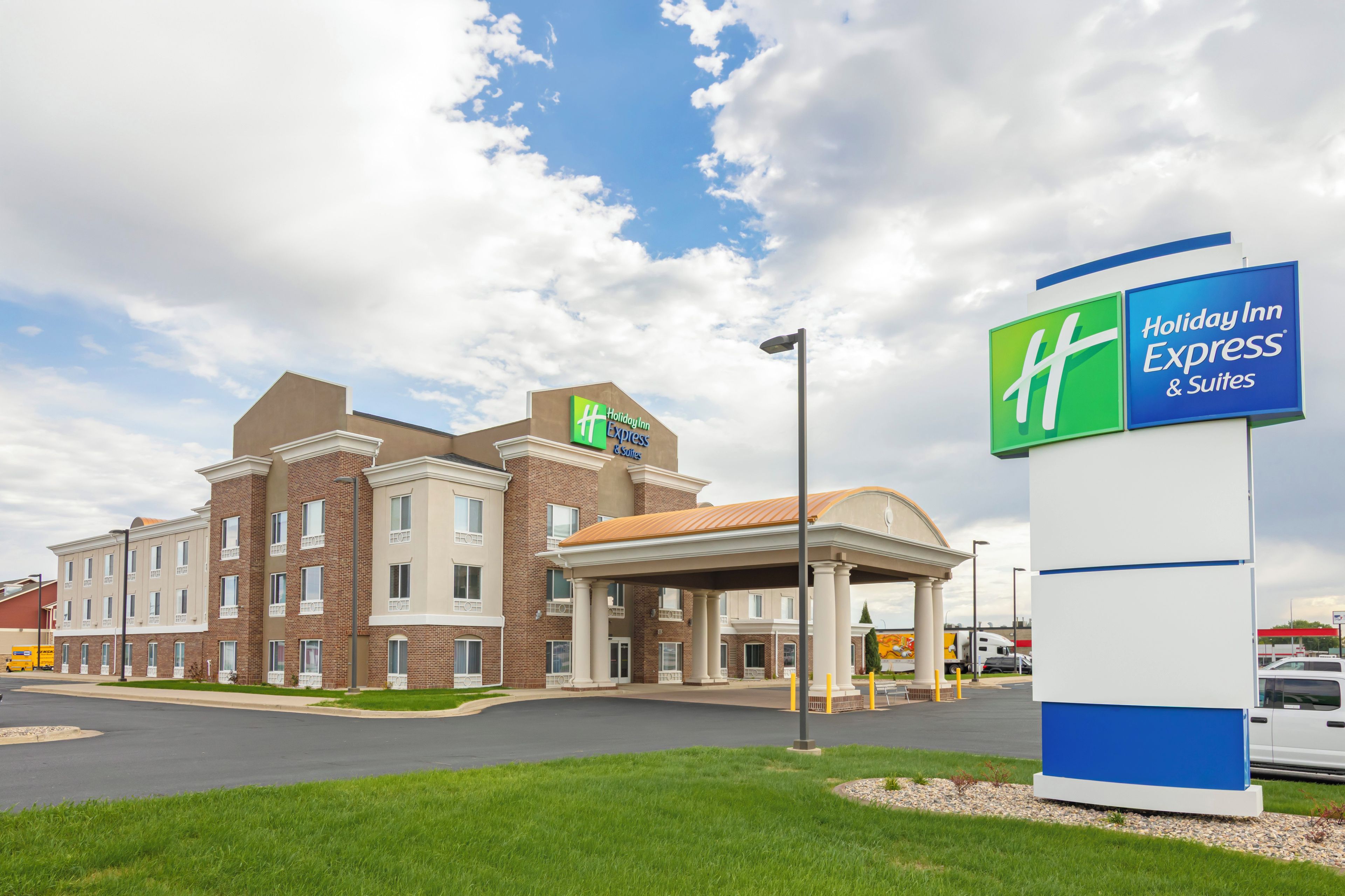 A Holiday Inn Express & Suites hotel with a brick facade, a covered entrance, and a clear sky.