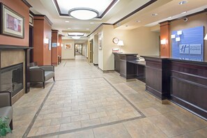 A hotel lobby with a reception desk, seating area, and a clock on the wall. - Holiday Inn Express & Suites Minot by IHG (Minot)