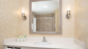 A bathroom with a large mirror, a sink, and two wall-mounted lights. - Holiday Inn Express & Suites Minot by IHG (Minot)