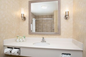 A bathroom with a large mirror, a sink, and two wall-mounted lights. - Holiday Inn Express & Suites Minot by IHG (Minot)
