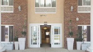 A building entrance with a number '300' above the door, potted plants on either side, and a non-smoking sign on the door. - Holiday Inn Express & Suites Minot by IHG (Minot)