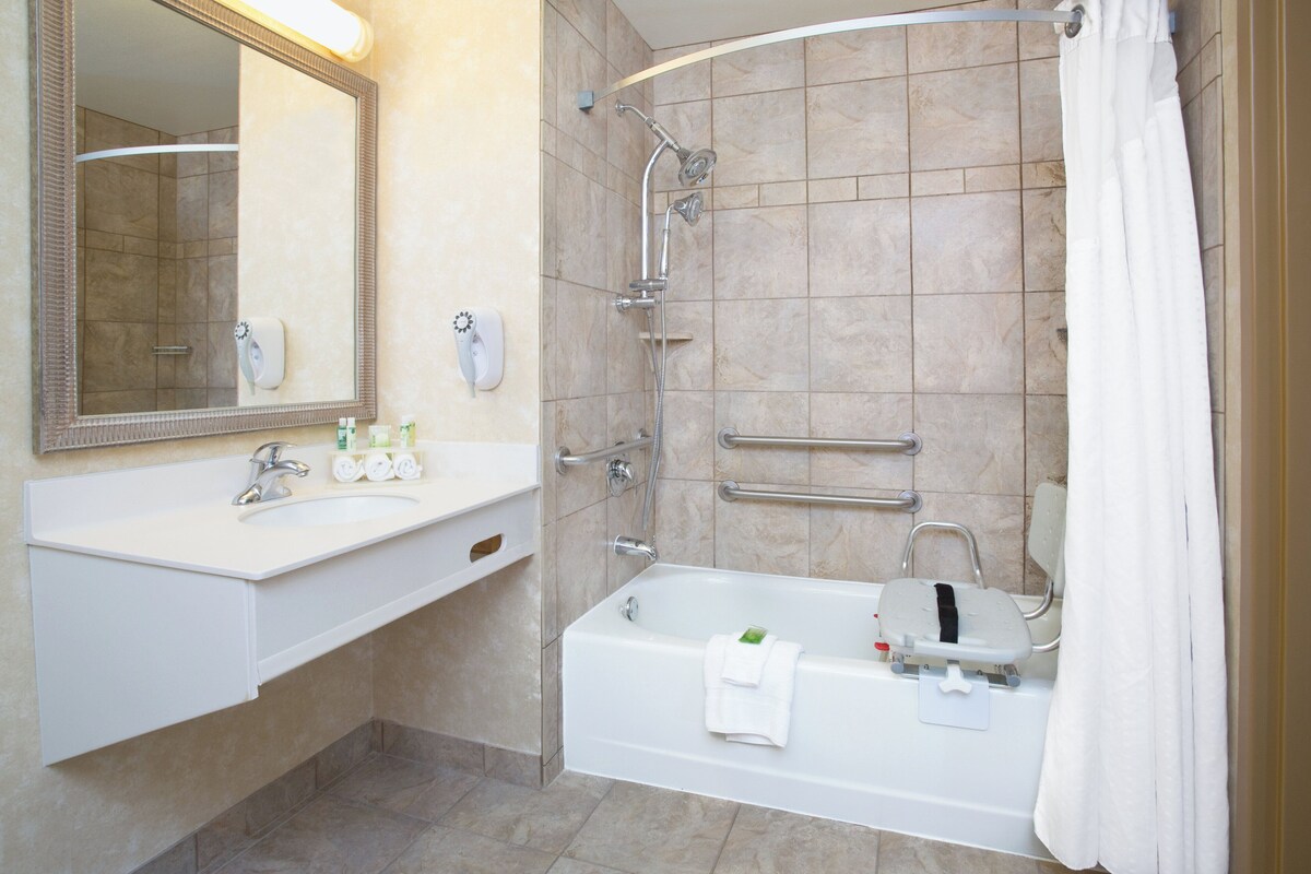 A modern bathroom with a sink, mirror, shower, and bathtub.