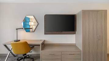 A modern hotel room with a wooden desk, a yellow chair, a wall-mounted TV, and a wardrobe.