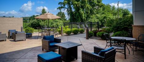 An outdoor patio area with wicker furniture, a table, and an umbrella.