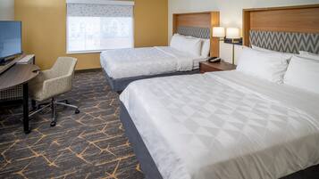 A hotel room with two beds, a desk, a chair, and a television.