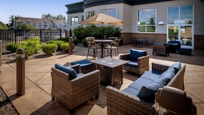 An outdoor patio area with wicker furniture, a table, and a large umbrella.