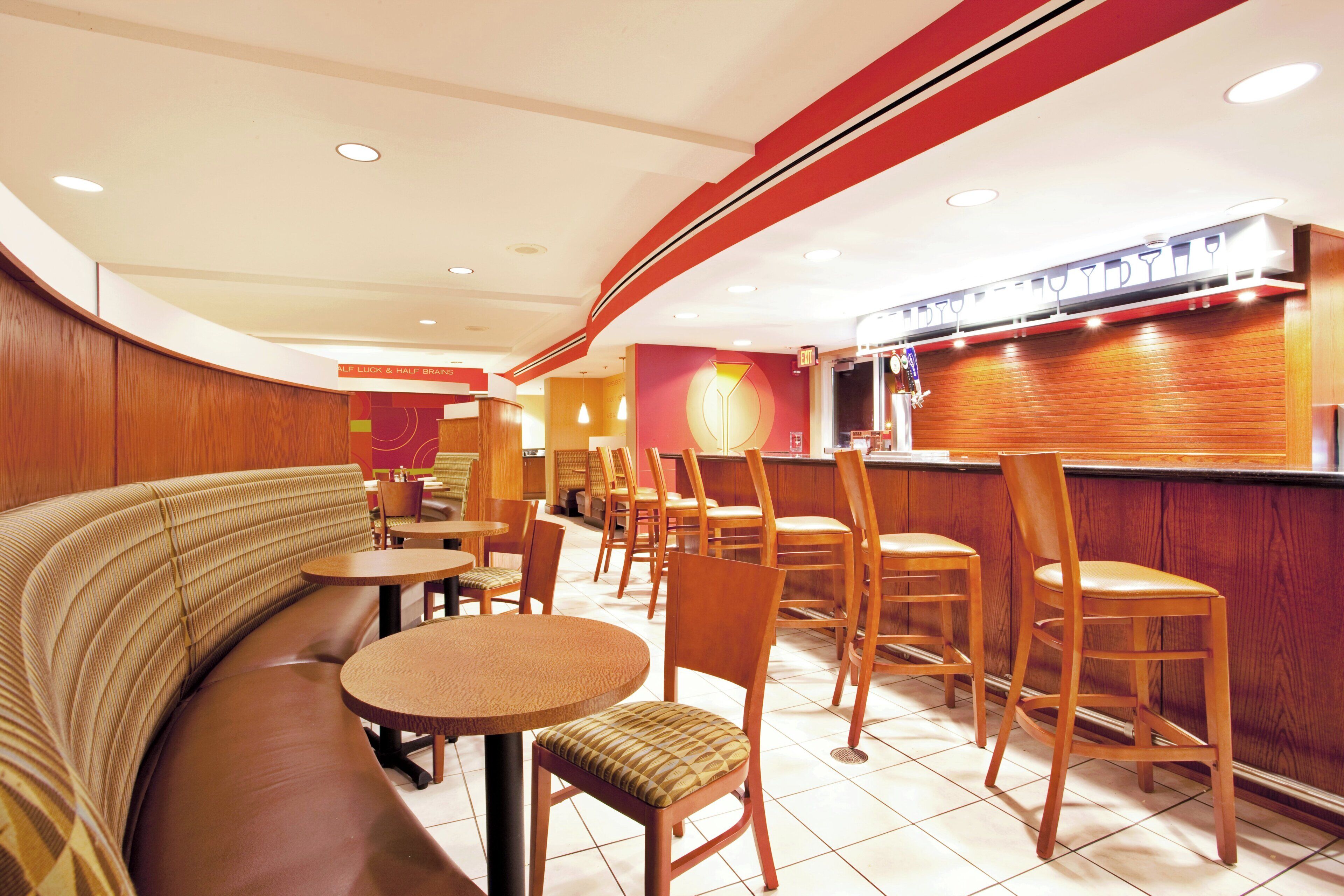 A restaurant interior with booths, round tables, and bar seating.