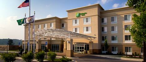 A Holiday Inn Express hotel with a covered entrance, American and Mexican flags, and handicap-accessible parking.