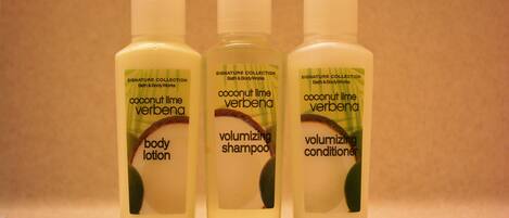 Three bottles of coconut lime verbena body lotion, shampoo, and conditioner.