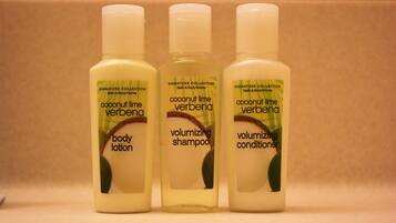 Three bottles of coconut lime verbena body lotion, shampoo, and conditioner.