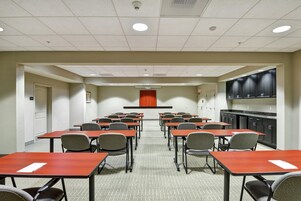 Un salón de conferencias con mesas y sillas dispuestas para reuniones.