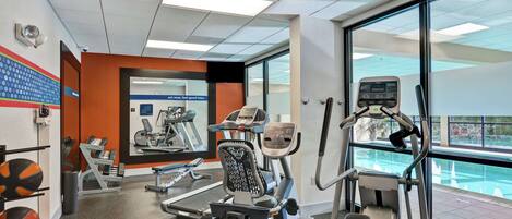 Une salle de sport équipée de tapis de course, de vélos elliptiques et de ballons d’exercice.