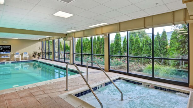 An indoor swimming pool with clear glass windows, a no diving sign, and a lifeguard chair. - Hampton Inn Lewisburg (Lewisburg)