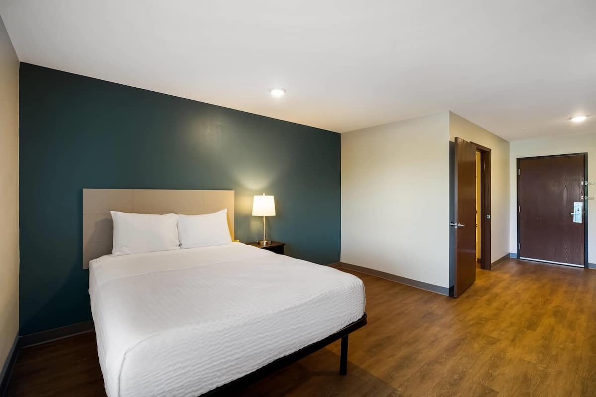 Une chambre d’hôtel avec un grand lit, une table de chevet avec une lampe et un plancher en bois.