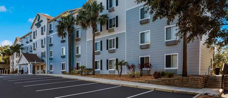 A multi-story hotel with a parking lot in front.