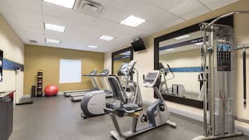 A gym with treadmills, elliptical machines, a weight machine, and a red exercise ball.