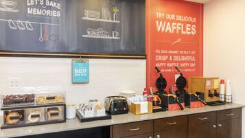 A bakery counter with waffle-making equipment and various baked goods displayed.