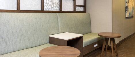 A seating area with a cushioned bench, a small table, and a decorative panel with artwork.