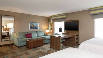 A hotel room with a bed, a sofa, a desk, a TV, and a large window.